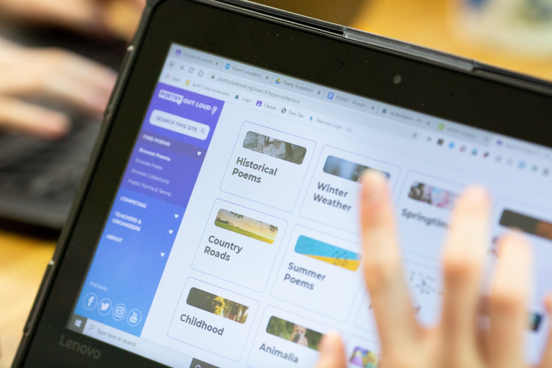A student at a laptop browsing a poetry site, the screen showing collections labelled Historical Poems, Winter Weather, Country Roads, Summer Poems and Childhood.